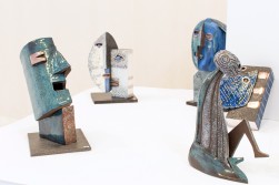 Cztery rzeźby: trzy ceramiczne głowy i siedząca postać ludzka