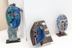 Zdjęcie przedstawiające fragment ekspozycji ceramiki. W ujęciu tym bardzo dobrze widoczne są trzy wystylizowane rzeźby ludzkich głów w różnych ujęciach.