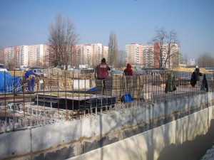 Na zdjęciu budowa nowej siedziby SDK. Widoczne betonowe elementy budowy oraz pracownicy budowy. W tle osiedle Służew nad Dolinką.