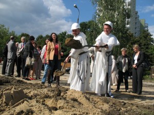 Na zdjęciu księża z zakonu o. Dominikanów podczas symbolicznego wbicia łopaty. W tle pozostali goście wydarzenia. 