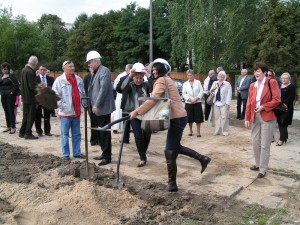 Na zdjęciu oficjalne wbicie łopaty. Na pierwszym planie p. Dyrektor Ewa Willmann podczas symbolicznego wbicia łopaty. W tle pozostali oficjalni goście wydarzenia. 