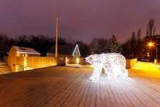 Zdjęcie wieczorową porą. Teren SDK. Na zdjęciu sztuczny, świecący biały niedźwiedź stojący przy amfiteatrze SDK. 