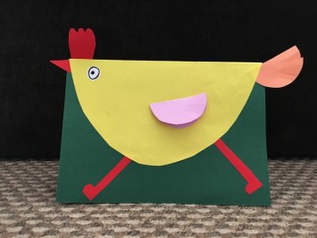 Zdjęcie przedstawia przykładową pracę plastyczną wykopnywaną na zajęciach: mały kurczak jest wykonany z żółtego półkola, ma cienkie czerweone nóżki z papieru, do tego grzykę, dziubek oraz różowy ogon i skerzydełko. Praca wykonana na zielonej kartce.