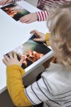 Dzieci przy stole oglądające abstrakcyjne fotografie. Fot. Marta Rybicka
