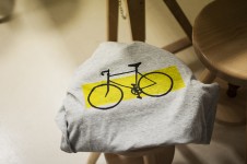 Na zdjęciu koszulka ozdobiona metodą sitodruku. Nadruk to rower na żółtym tle. 