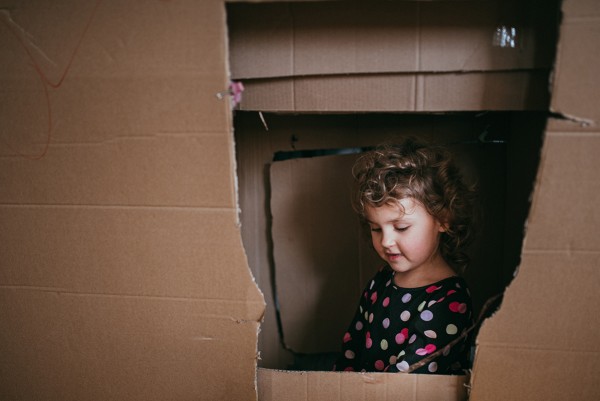 Ukrywanie chaosu dzięki ramie: przestrzeń kadru wypełnia wielki karton, w jego wnętrzu siedzi i bawi się kilkuletnia dziewczynka. Fot. Agnieszka Mocarska