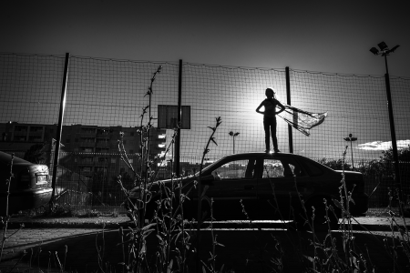 Na zdjęciu znajduje się auto na którym stoi nastoletnia dziewczynka w stroju supermenki na tle boiska. Fot. Agnieszka Mocarska
