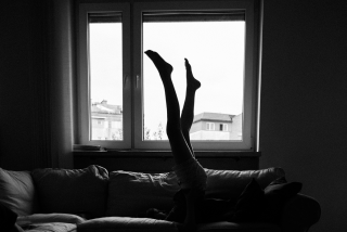 Na zdjęciu sylwetkę człowieka leżącego na kanapie i unoszącego nogi, które wyraźnie widać w ramie okna. Fot. Agnieszka Mocarska