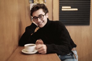 Na zdjęciu Michał Korkosz  siedzący przy stoliku z pączkiem i kawą. Fot. Karo Ramos