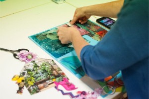 Zdjęcie przedstawia kobietę podczas pracy nad wycinaniem kolorowych elementów do swojego kolażu.