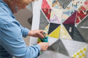 Zdjęcie przedstawia kobietę projektującą patchwork z kawałków tkaniny