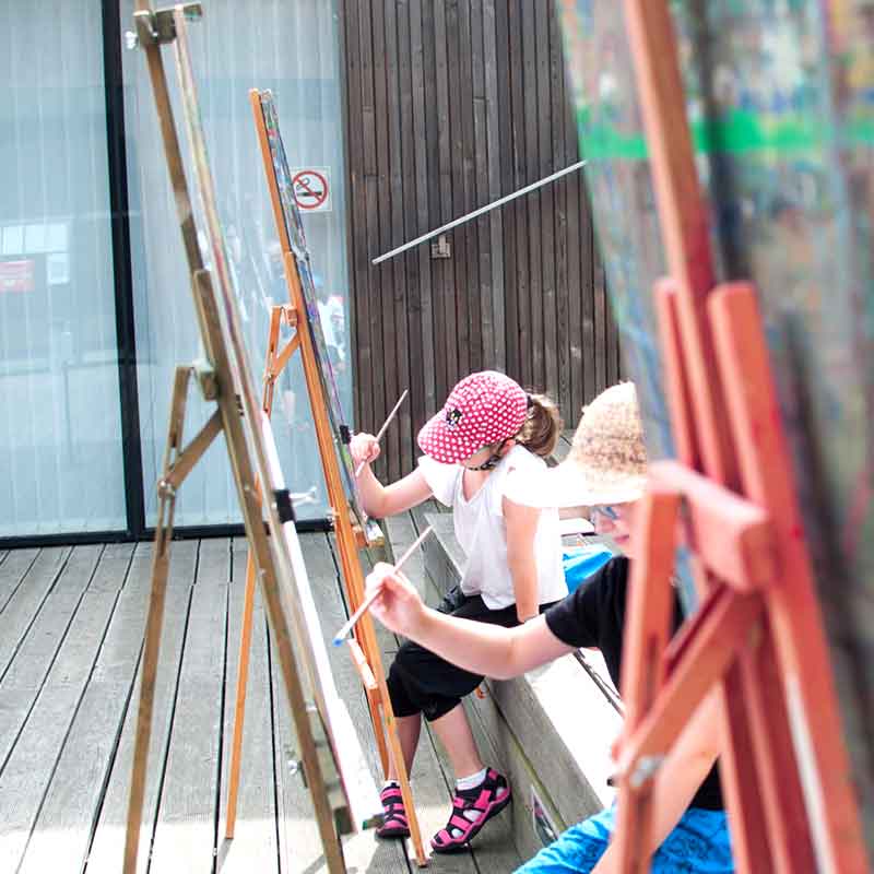 Dzieci malujące przy sztalugach w amfiteatrze SDK